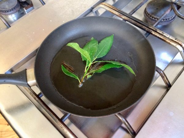 Place 1 tablespoon of each of the oils in a skillet over medium-high heat. Place one bay leaf in the pan and when it begins to sizzle, add the branch or remaining bay leaves to the pan and cook them until they begin to blacken and smoke, which will take 3 to 4 minutes.